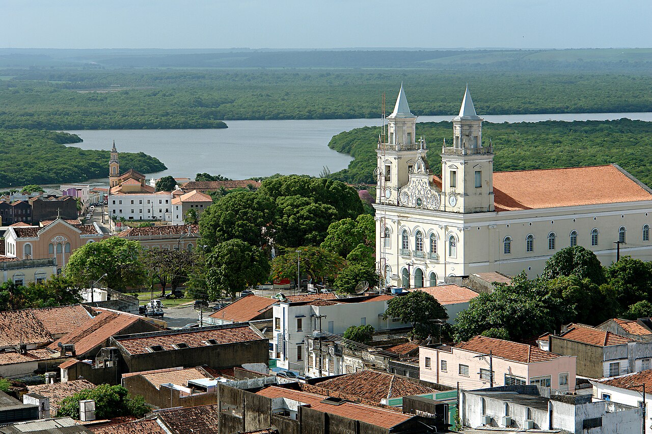 Centro Histórico de João Pessoa com a Catedral Basílica de Nossa Senhora das Neves e um rio cercado de vegetação ao fundo